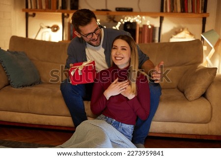 Cheerful young woman receiving a gift from her boyfriend
