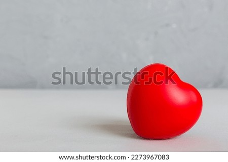 gift box with red bow and red heart on colored background. Perspective view. Flat lay.