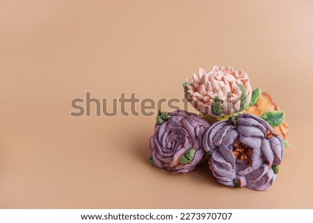 On wooden round background lie natural marshmallows in the form of purple peony flowers. Sweet desserts without sugar. Creative baking confectioners. Copy space, mock up. Sweet food. Isolated orange