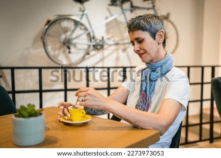 One woman senior caucasian female sit at cafe or restaurant have a cup of coffee real people copy space modern gray short hair person sitting alone Royalty-Free Stock Photo #2273973053