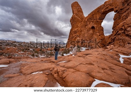 Man hiking in the red mountains. Man taking pictures of Turret Arch on the Windows Loop Trail. Arches   National Park, Utah, USA
