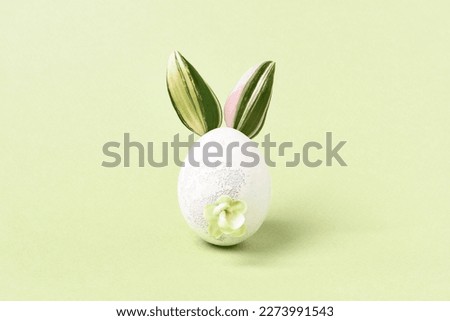 Easter bunny. Decorated Easter egg. Green leaves as ears and flower tail. DIY gift idea. Easter greeting card, pastel, minimal.