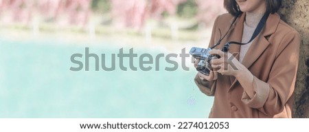 Banner Close up hands Asian Women look at dslr digital camera vintage film style take a photo. Female photographer look at picture outdoor. Woman hands shooting photo in green park with copy space