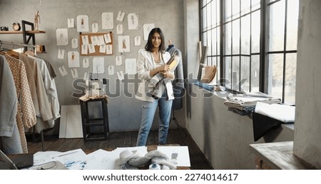 Young Confident Asian Entrepreneur woman or female professional fashion stylist is holding a pattern in hand in designer office looking at camera. Self-employment, Startup concept