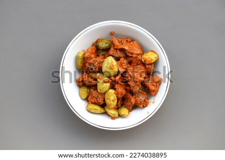 Indonesian traditional food named "sambal goreng ati ampela pete" i.e. Hot spicy chicken gizzard and heart cooked with bitter bean served on plate isolated on gray background, top view  Royalty-Free Stock Photo #2274038895