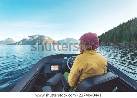 Woman Driving Motor Boat at Sunset in Coastal British Columbia in Nature Landscape Near Bute, Toba Inlet and Campbell River. Whale Watching Tourist Travel Destination, Canada Royalty-Free Stock Photo #2274040441