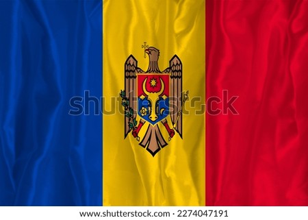 The flag of Moldova on a silk background is a great national symbol. Texture of fabrics The official state symbol of the country