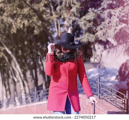 Pretty girl on a walk in red coat in city