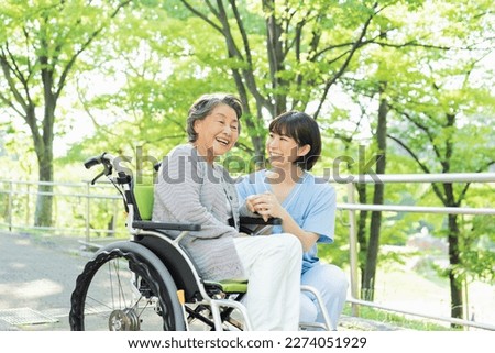 Senior woman in wheelchair indoors with Female health care worker in her 30s