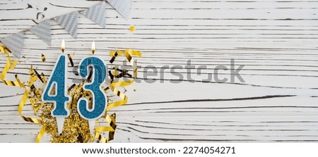 Number 43 blue celebration candle on white wooden background. Happy birthday candles. Concept of celebrating birthday, anniversary, important date, holiday. Copy space. Banner