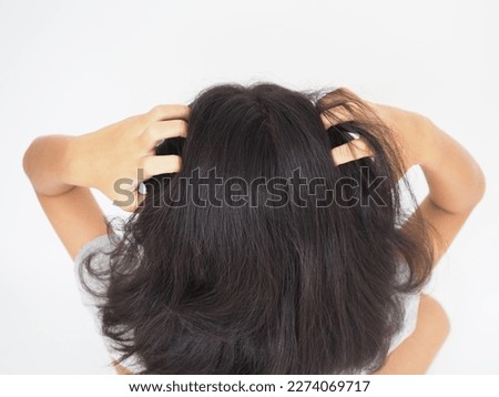 Little girl is scratching her head on white background. Top view photo, blurred.