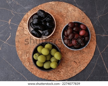 Flat lay food photography of cold appetizers. types and varieties of olives, taggiasca olive, baked black olives, sweet green olives on the black marble background with a copy space. 