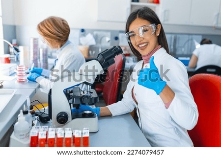 Young scientists conducting research investigations in a medical laboratory, a researcher in the foreground is using a microscope