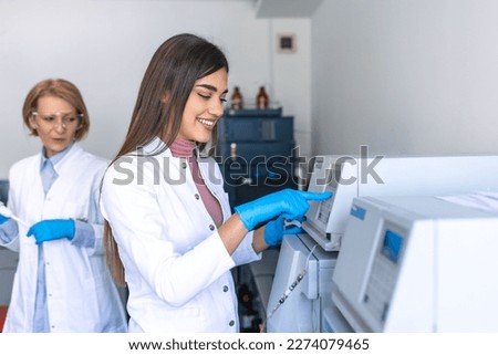 Two Research Scientists Talking about Programming Medical Equipment for Tests. Team of Professionals Doing Pharmaceutical Research in Modern Laboratory