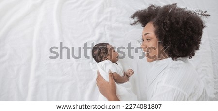 Closeup portrait of beautiful young African American mother day girl kiss healthy newborn baby sleep in bed flat lay copy space. Healthcare medical love black woman lifestyle mother's day, top view