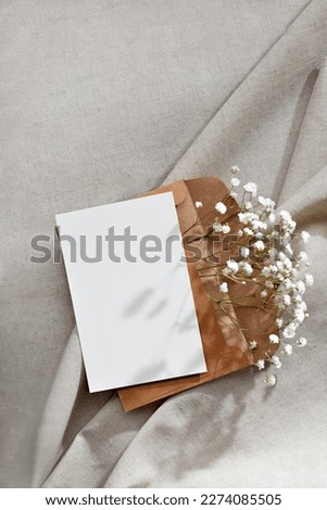 Blank paper card and envelope with flowers on a neutral beige background, congratulation, invitation or greeting card template with mockup copy space