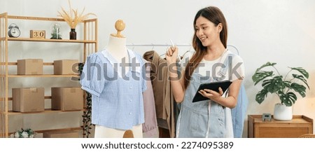 Female fashion designer is checking detail of dress on mannequin after designing and sketching new collection of clothes on tablet in the studio.