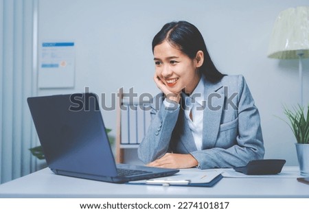 Young Asia business woman working with annual summary report and laptop to planner analyze data of balance sheet charts, bookkeepers female people concept. Using laptop