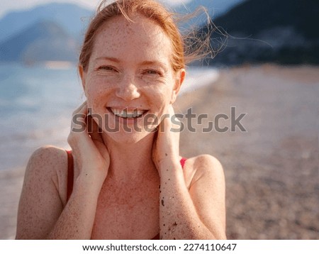 Beautiful ginger woman in red bikini on tropical beach. Portrait of happy young lady smiling at sea. Happy girl with red hair and freckles enjoying the sun. concept of safe interaction with sun Royalty-Free Stock Photo #2274110647