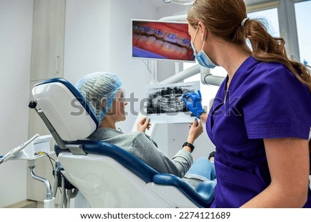 A professional dentist shows the patient pictures of his jaw and teeth. The concept of pictures of the jaw and teeth at the dentist