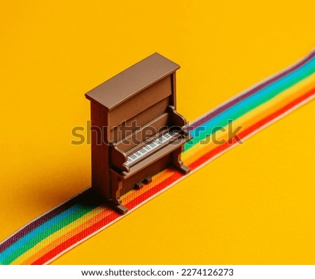 a toy piano stands on a rainbow colored strip 