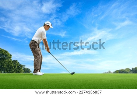 Golf approach shot with driver on golfing ground with blue sky background.
