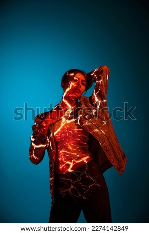 Lightning discharge imitation. Futuristic style portrait of young woman with digital neon filter lights on clothes over blue background. Concept of art, fashion, cyberpunk, futurism and creativity.