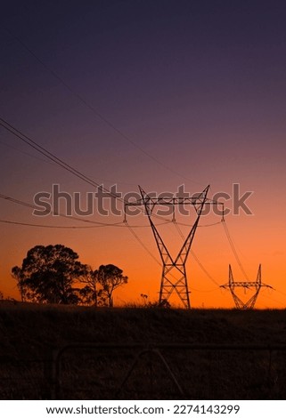 Electricity Power line pylons silhouetted against the sunrise Royalty-Free Stock Photo #2274143299