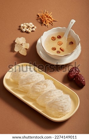 Advertising photo with bird’s nest, jujube, rock sugar, lotus seeds and Cordyceps on brown background. Herbs from nature, good for health, precious and expensive. Royalty-Free Stock Photo #2274149011