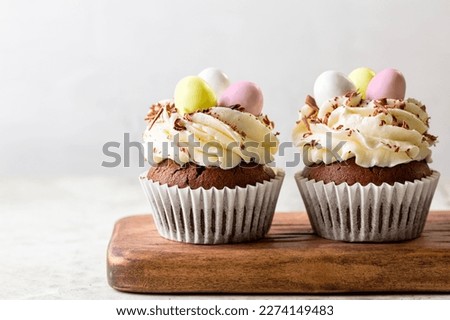 Easter chocolate cupcakes with cream cheese, sweet candy eggs and nest. Holiday homemade dessert. Close-up. Royalty-Free Stock Photo #2274149483