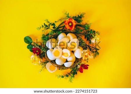 Easter picture with cupcakes in the form of Easter eggs,on a yellow background in a basket with flowers.Baking in the form of eggs covered with white chocolate,a fashionable alternative to Easter cake