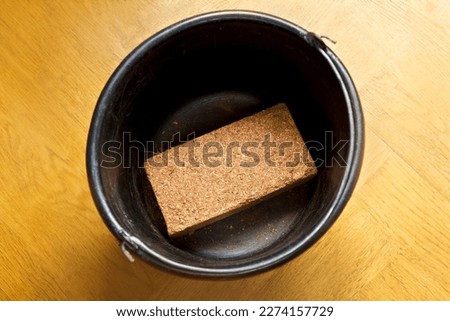 How to make cheap and eco-friendly grow or potting soil from coconut bricks, step 1: place the dry block of compressed coco coir in a suitable bucket. Royalty-Free Stock Photo #2274157729