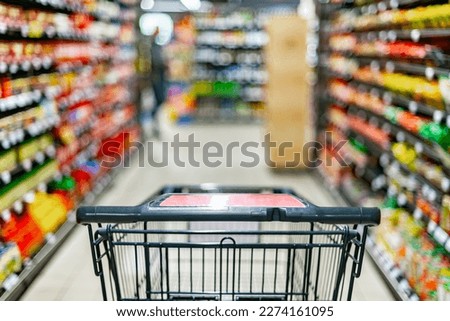 A shopping cart by a store shelf in a supermarket