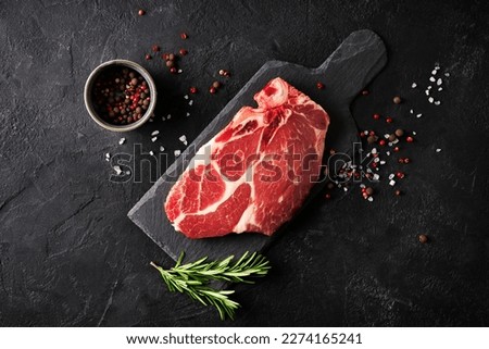 Raw fillet meat pork on board with peper seasoning and green rosemary on black background, top view, close up Royalty-Free Stock Photo #2274165241