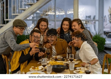 Group of Asian people using mobile phone taking selfie together during outdoor celebration dinner party in the garden on summer holiday vacation. Man and woman friend reunion meeting at restaurant. Royalty-Free Stock Photo #2274171627