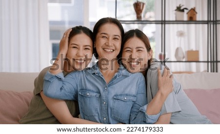 Happy good warm time Mother day two grown up kid child looking at camera cuddle hug arm around mature mum. Love kiss care mom asia middle age adult three people smile enjoy sitting easy at home sofa