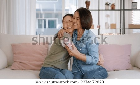 May Mother's day young adult grown up child cuddle hug give flower gift box red heart card to mature middle aged mum. Love kiss care mom asia people sitting at home sofa happy smile enjoy family time. Royalty-Free Stock Photo #2274179823