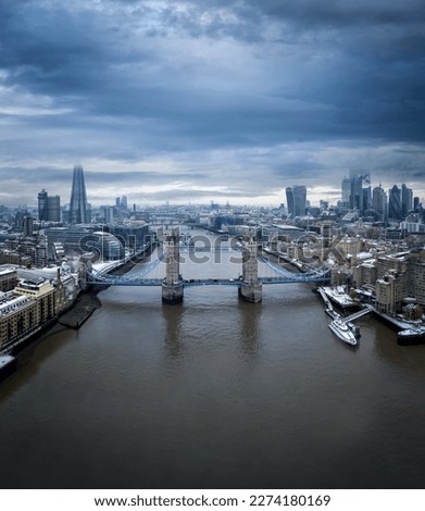 Aerial view of the snow covered skyline of London with Tower Bridge in the front and the skyscrapers of the City behind during a cold winter morning