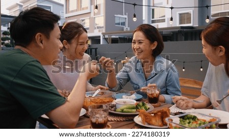 Mom enjoy thai meal cooking for family day meet talk home dining at dine table cozy patio. Group asia people young adult man woman friend fun joy relax warm night time picnic eat yummy food with mum. Royalty-Free Stock Photo #2274180319