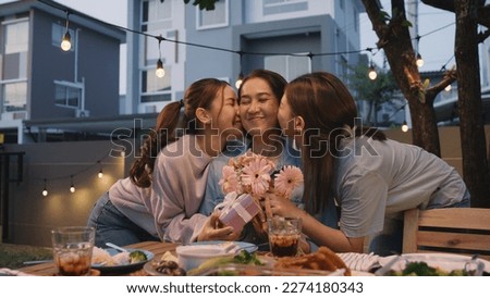 Mother's day two young child cuddle hug give flower gift box to mature mum. Love kiss mom asia people middle aged adult at home cozy dining table night dinner party happy smile enjoy relax warm time. Royalty-Free Stock Photo #2274180343