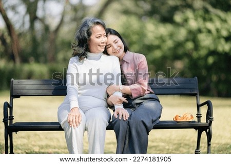 Happy adult granddaughter and senior grandmother having fun enjoying talk sit with green nature. in garden 