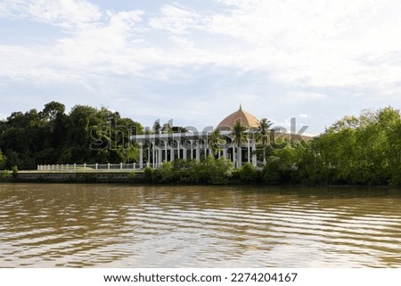 trees, boat and building along Sungai Kedayan river, the capital of Brunei Darussalam in sunny day with white coulds and blue sky