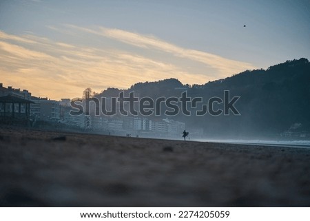 Girl with surfboard on the sand at the blue hour