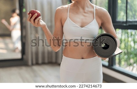 Fitness woman holding yoga mat with Fresh Apple Heathy clean vegan food before working out in yoga studio. Royalty-Free Stock Photo #2274214673
