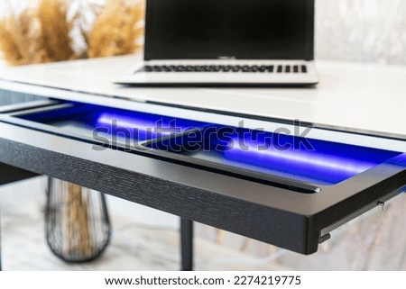 Top view of open wooden drawer office table with blue lightning. Modern office table with light