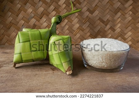 Close up view of Ketupat and rice, an Indonesian traditional cuisine very popular during Hari Raya Idul Fitri. Ketupat is a natural rice casing made from young coconut leaves for cooking rice. Royalty-Free Stock Photo #2274221837