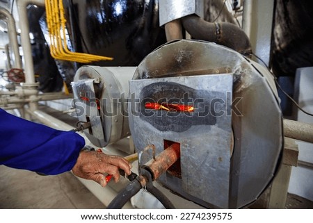 Closeup photo of biogas plant furnace flame and operator's hand