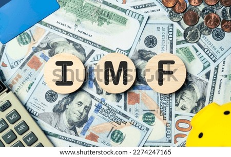 IMF text in wooden circle on Banknotes background, credit card, piggybank, calculator. International Monetary Fund, planning goals, opportunity, challenge, business strategy and financial concept. Royalty-Free Stock Photo #2274247165