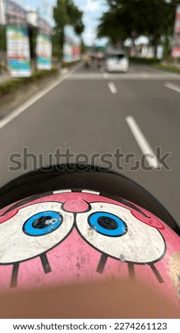 a motorbike rider's helmet is pink, with the shape of a cartoon series.  with focus and blur camera effects Royalty-Free Stock Photo #2274261123