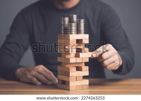 Risks in business or financial concept. Idea to prevent risk in business. Business man playing and selective right or risky piece of tower wooden block game and prevent falling down. Studio shot. Royalty-Free Stock Photo #2274263253